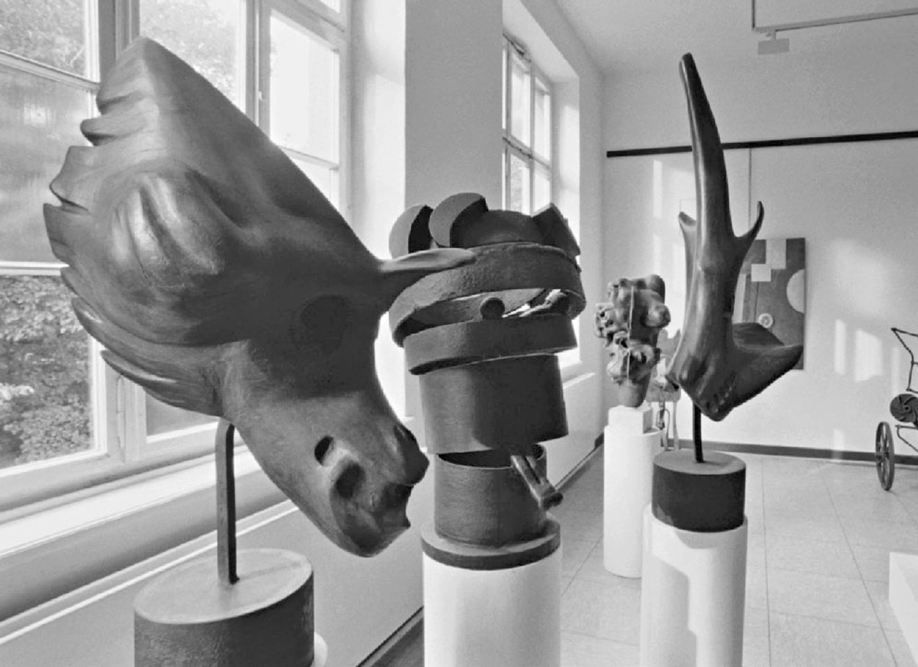 Skulpturen aus Metall auf einem zylinderförmigen Sockel des Künstlers Lungwitz. Seine Objkete sind im Museumsgebäude aufgestellt.