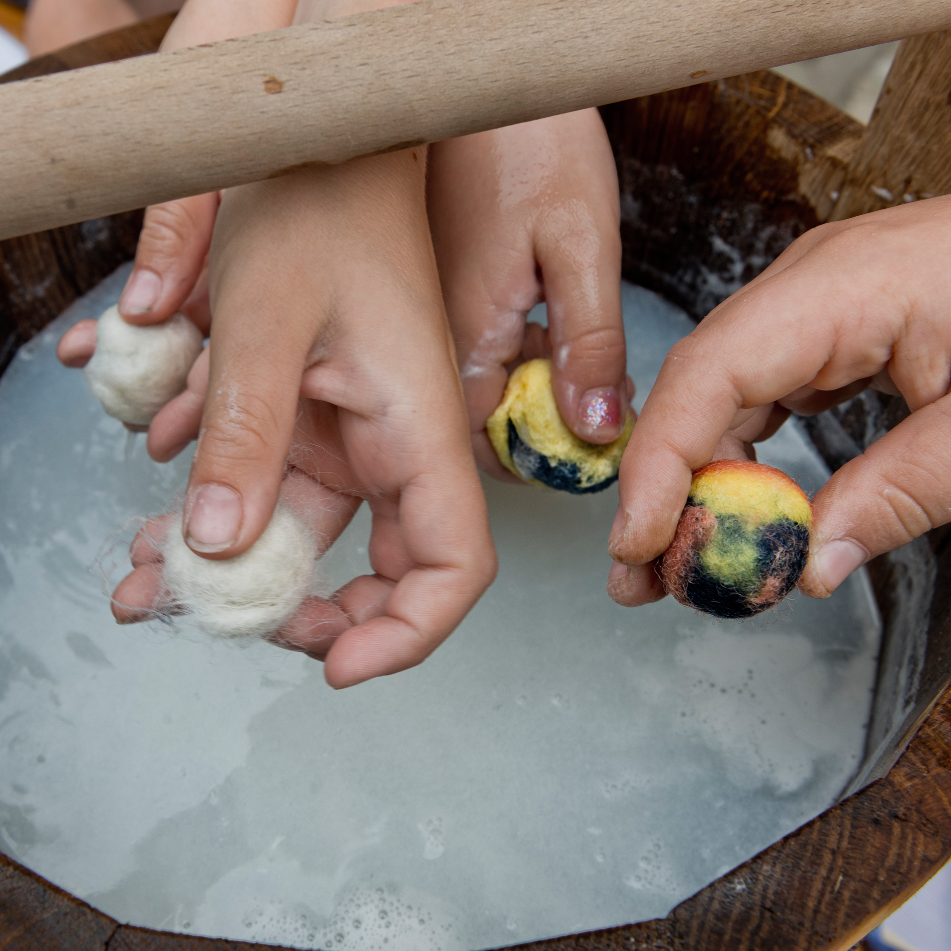 Filzkugeln werden in einem Wasserbottich mit den Händen gefilzt
